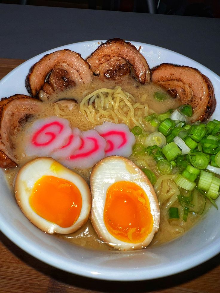 a bowl filled with ramen and eggs on top of a wooden table