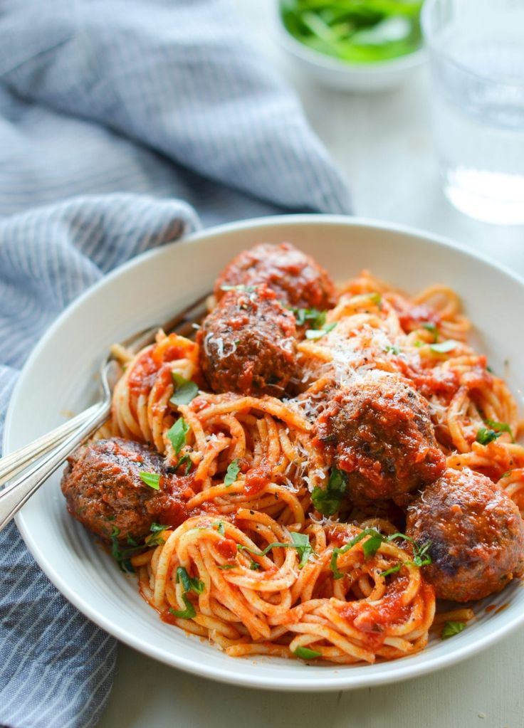 spaghetti with meatballs and tomato sauce in a white bowl