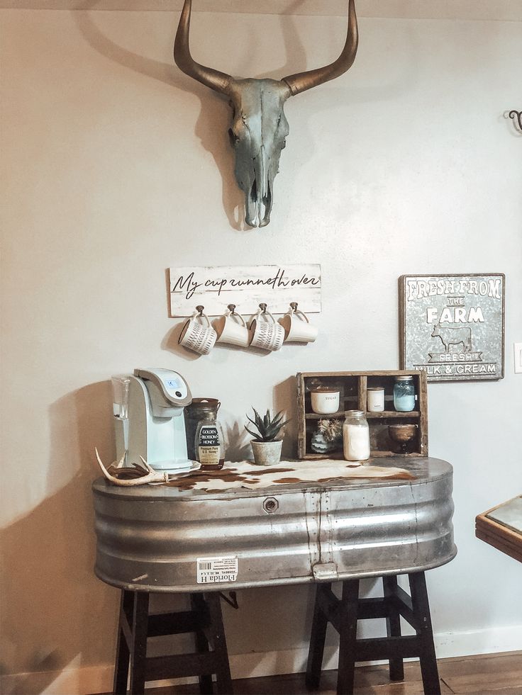 a metal table topped with lots of stuff next to a wall mounted cow skull on the wall