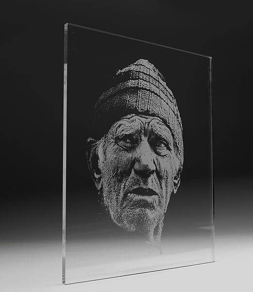 a black and white photo of an old man's face on a glass block