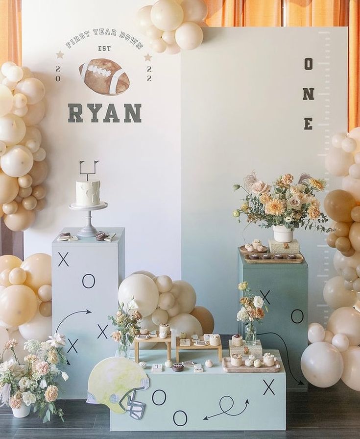 balloons and decorations are arranged on display in front of a wall with an american football theme