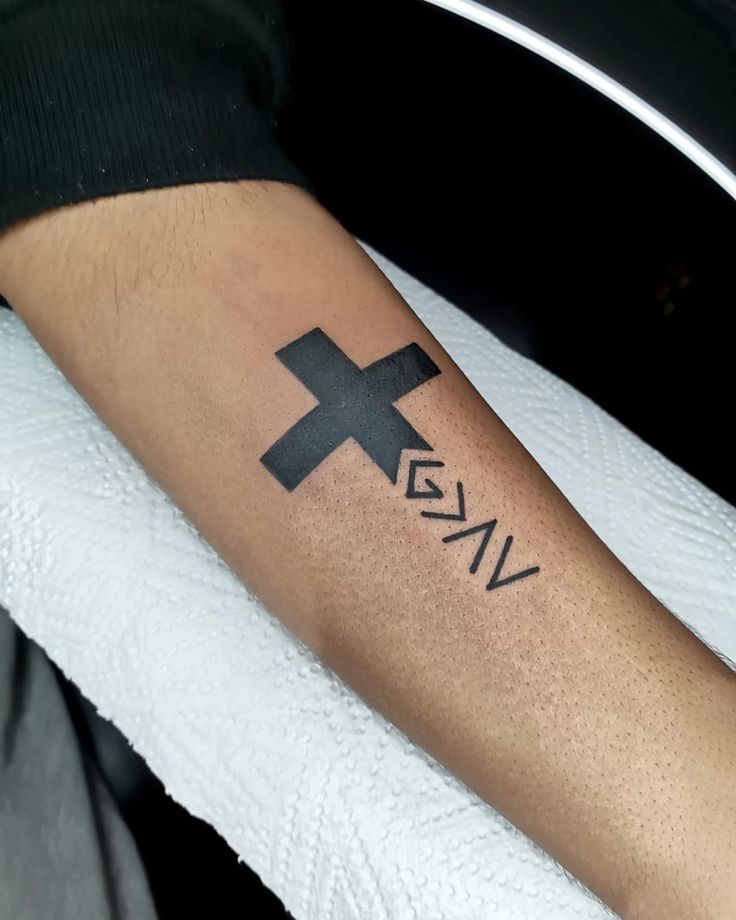 a person with a cross tattoo on their arm