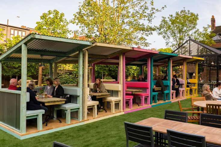 people are sitting at tables and eating outside in an outdoor area with grass on the ground