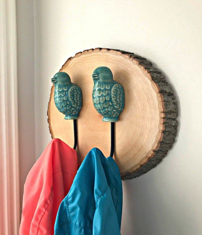 two blue and red birds are on the wall next to a coat rack with three coats hanging from it