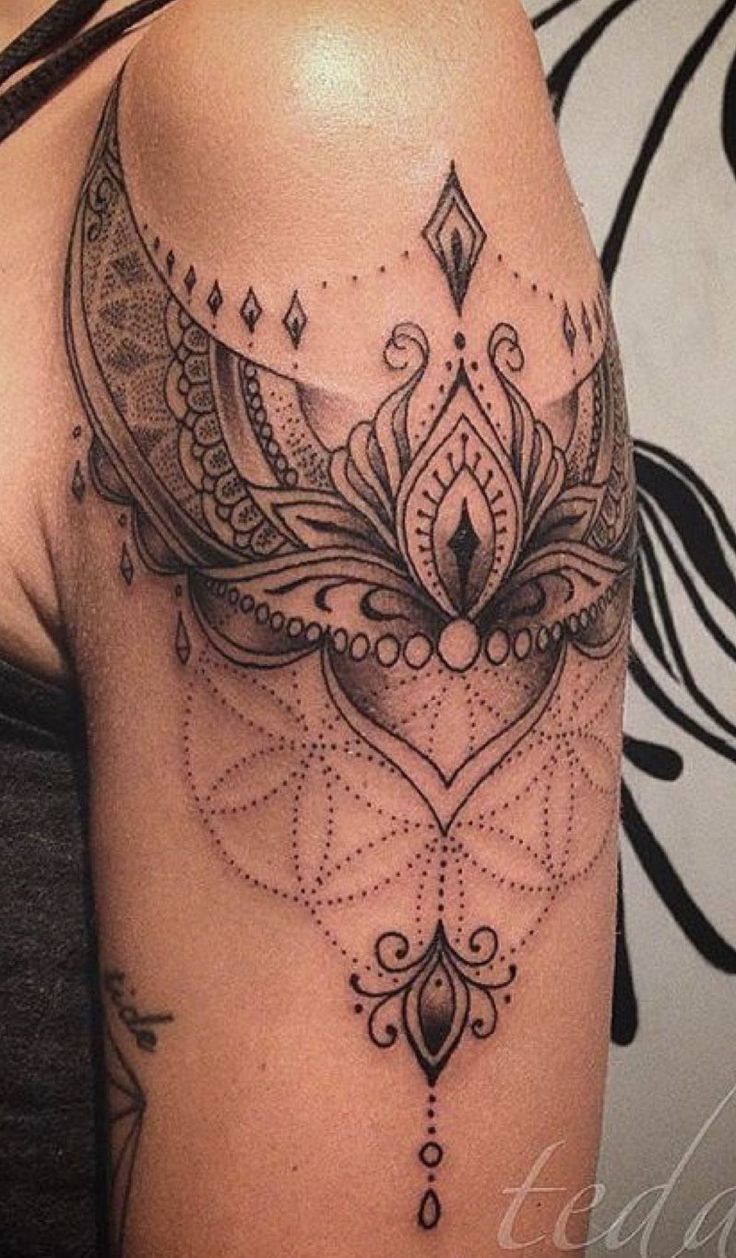 a woman's arm with an intricate tattoo design on the left side of her shoulder