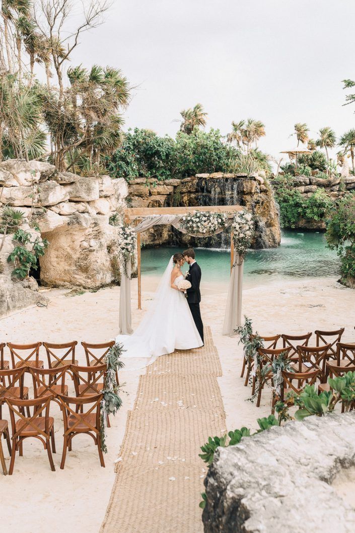 a bride and groom standing in front of an outdoor wedding ceremony setup with wooden chairs