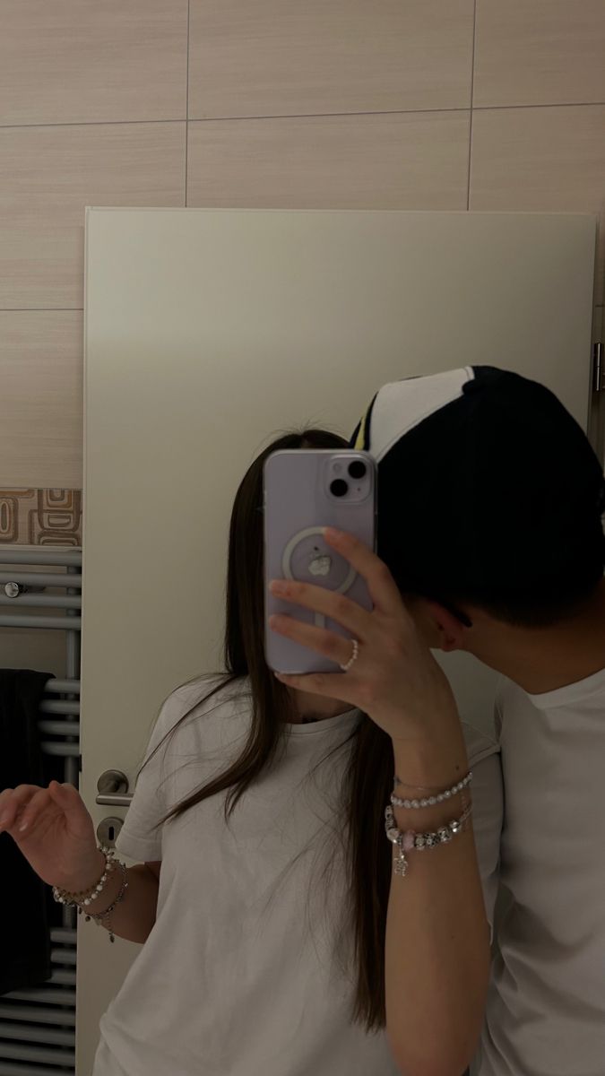 a woman taking a selfie in front of a mirror with her cell phone up to her ear