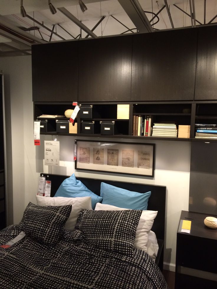 a bed with black and white comforter in a bedroom next to a book shelf