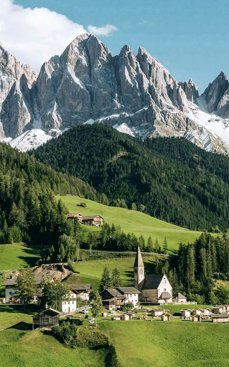 the mountains are covered in snow and green grass, with small houses on each side