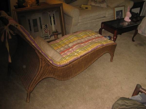 a wicker chaise lounge chair in a living room