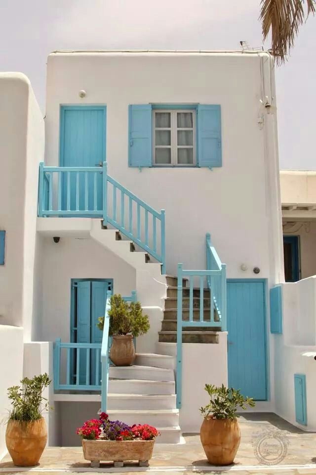 blue and white house with potted plants in front