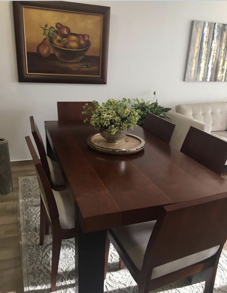 a dining room table with chairs and a bowl of fruit on top of it in front of a couch