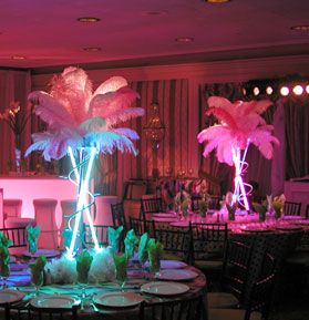 the tables are decorated with palm trees and pink lights in the background is a banquet room