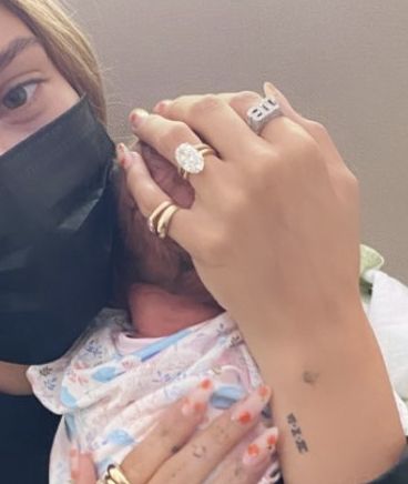 a woman holding a baby wearing a face mask