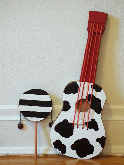 a ukulele with black and white spots on it next to a red stick