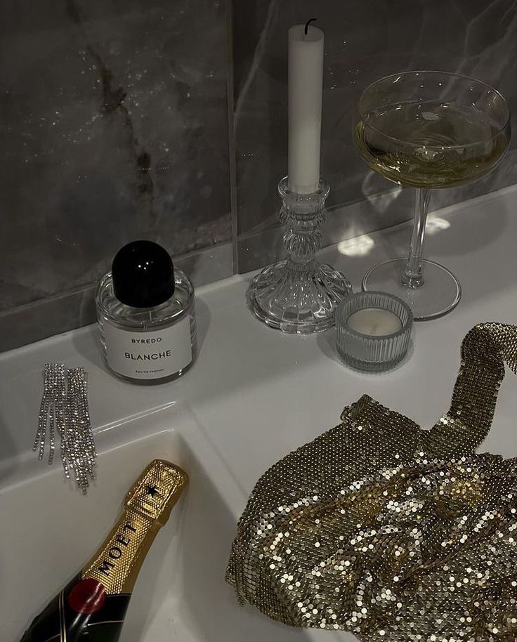 a bath room with a sink and a bottle of wine next to a candle holder