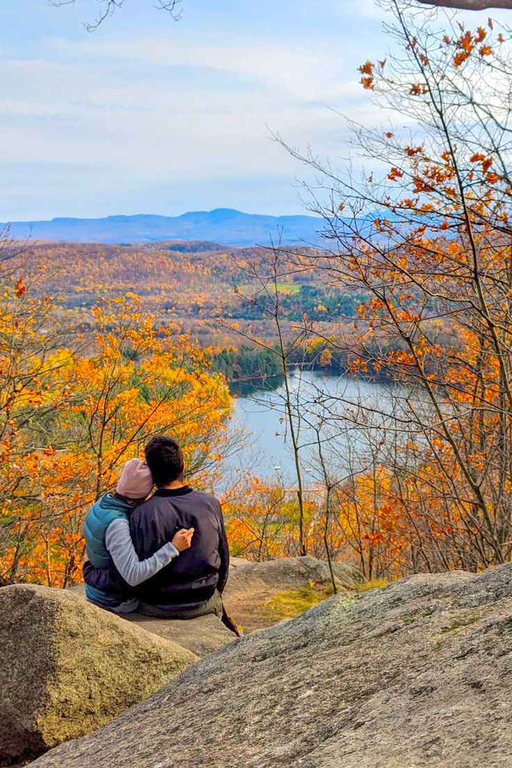 a couple is sitting on some rocks on the top of a mountain overlooking a fall scene in quebec. The trees are changing to orange around them and they are looking on to a lake with trees around it. In the distance is a mountain range. They are wearing jackets and hats to stay warm. Fall Afternoon Tea, Montreal Fall, Montreal Things To Do, Things To Do In Montreal, September Colors, Fall Afternoon, Tea Reading, Of Montreal, Fall Travel