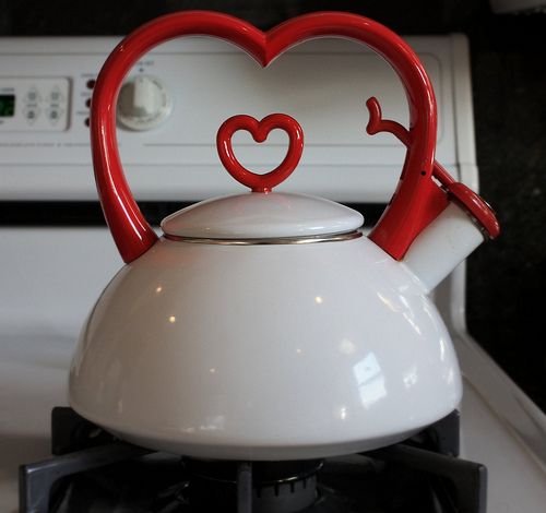 a tea kettle with two red hearts on it sitting on top of a stovetop