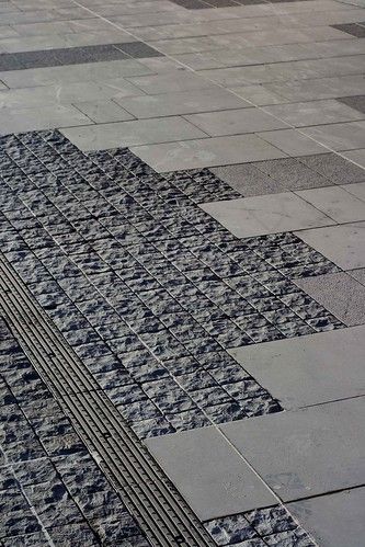 an umbrella sitting on top of a tiled sidewalk