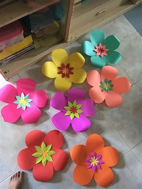 paper flowers laid out on the floor with one person's feet next to them