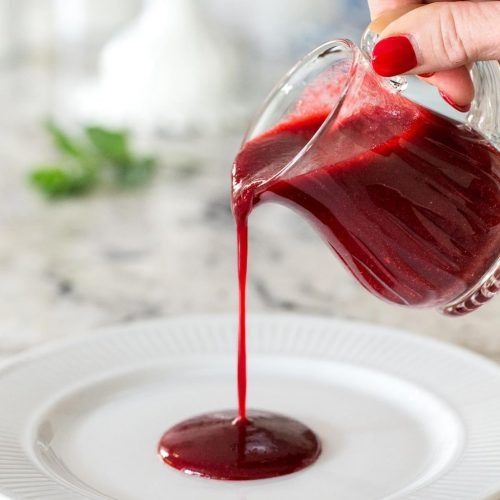 someone pouring red liquid into a white plate