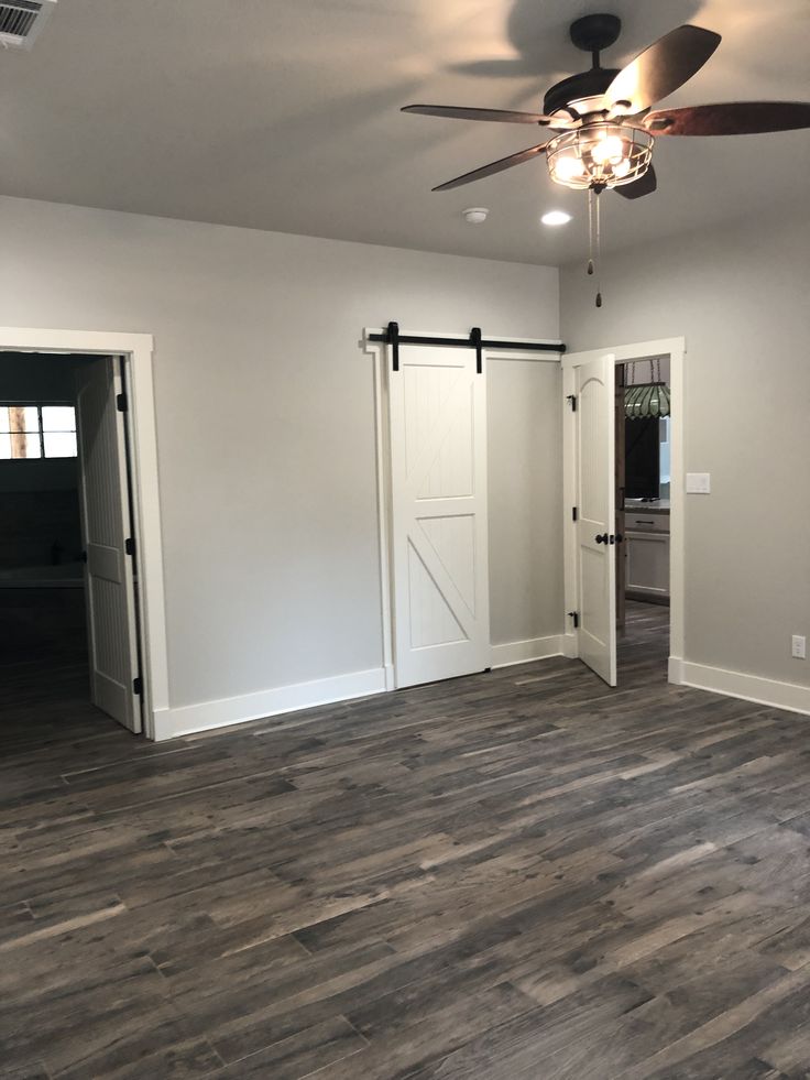 an empty living room with wood floors and ceiling fan