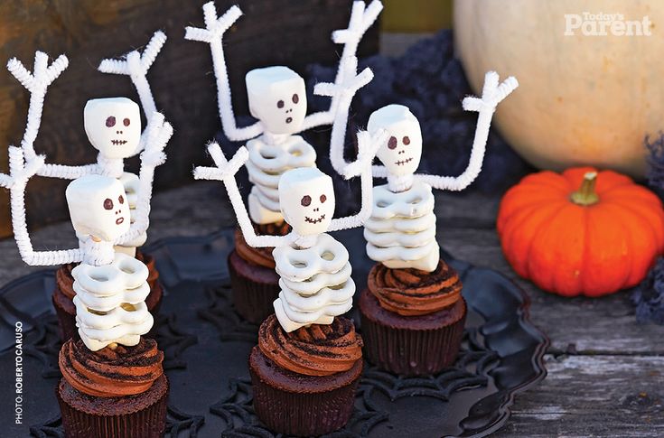 cupcakes decorated with white frosting and skeleton decorations on top of each other