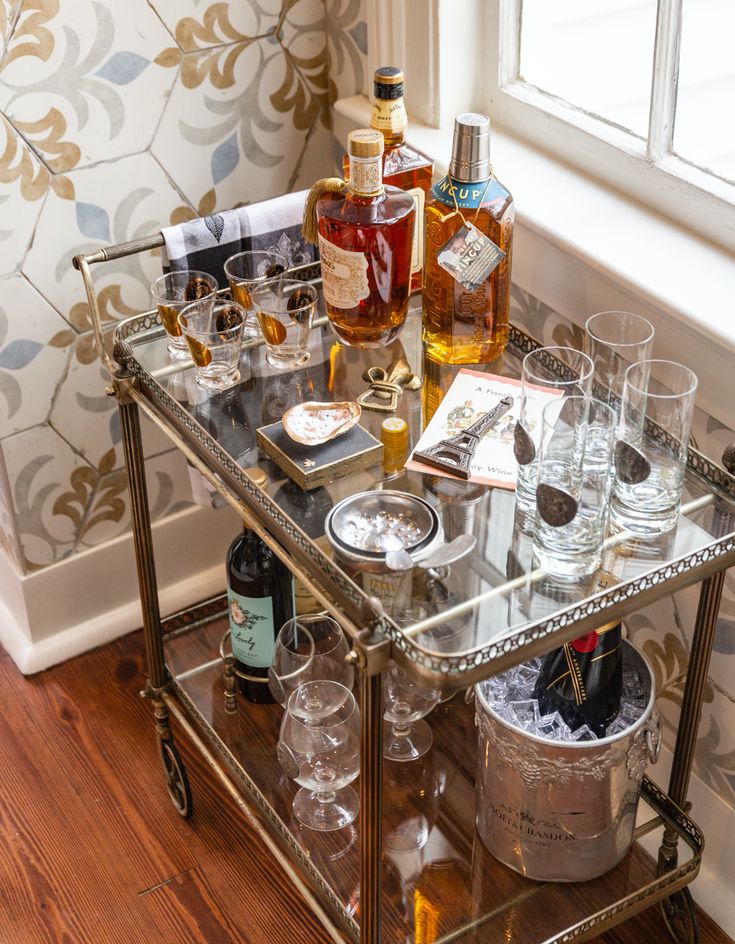 a bar cart filled with liquor bottles and glasses on top of a hard wood floor