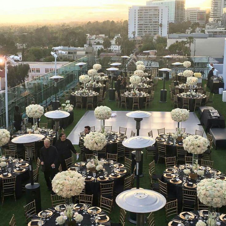 tables and chairs set up for an event on the roof of a building with tall buildings in the background