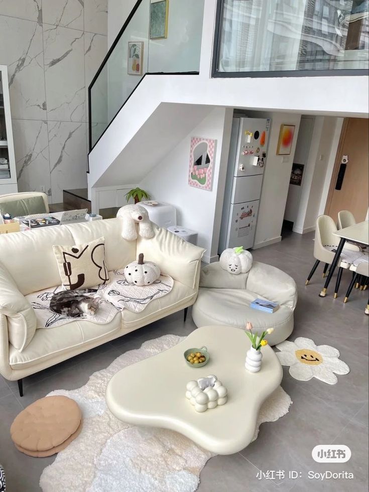 a living room filled with white furniture next to a stair case in a home office