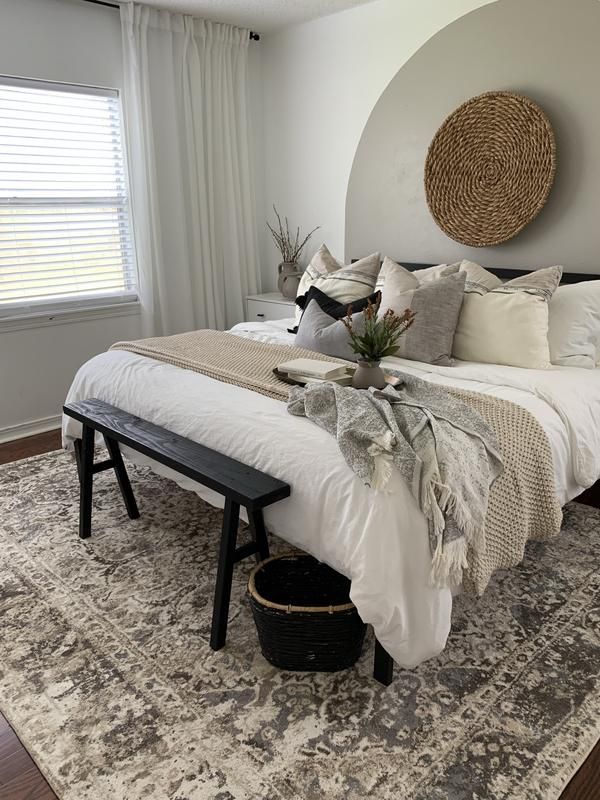 a bedroom with a bed, bench and rug on the floor in front of it