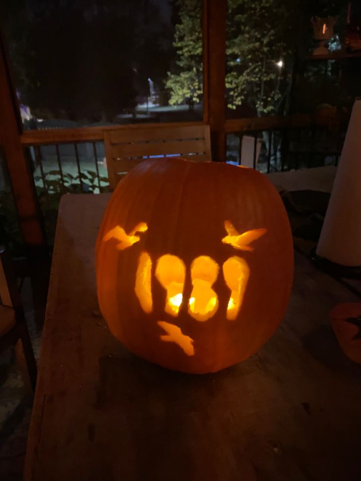 a carved pumpkin sitting on top of a wooden table with candles in the shape of faces