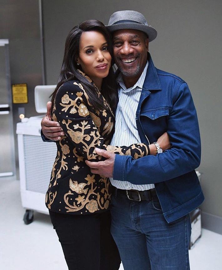 a man and woman hugging each other in front of a white wall with an elevator behind them