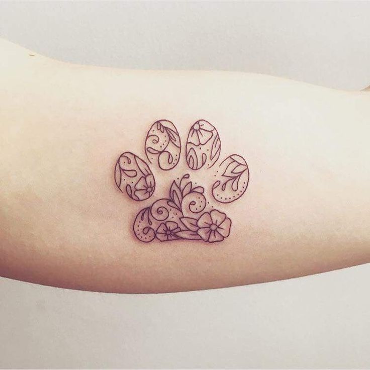 a dog paw tattoo on the left upper arm and lower arm, with an animal's paw surrounded by flowers