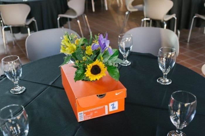 an orange box on top of a table with wine glasses and flowers in the center