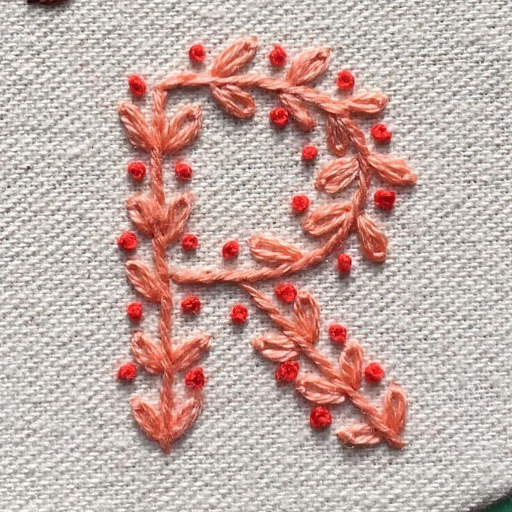 an embroidered letter is shown with red beads