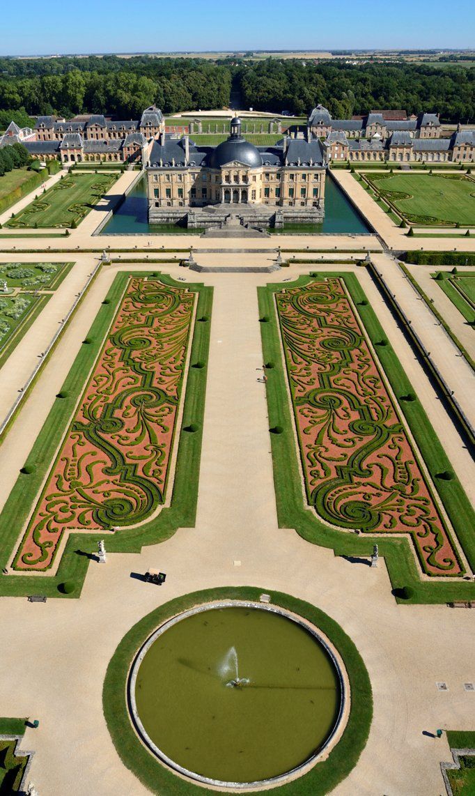 an aerial view of a large building in the middle of a garden with a fountain