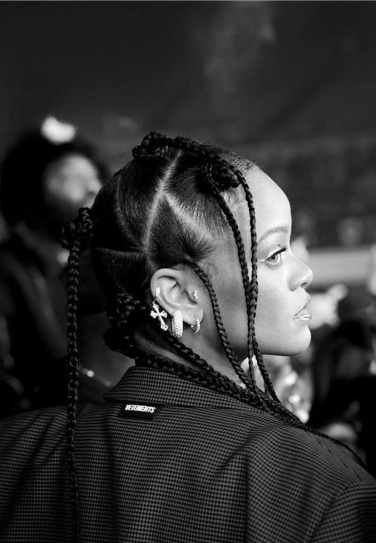 a black and white photo of a woman with cornrows in her hair looking off into the distance