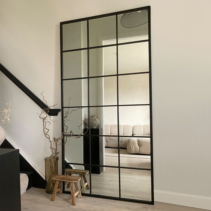 a mirror sitting on top of a wooden floor next to a stair case in a living room