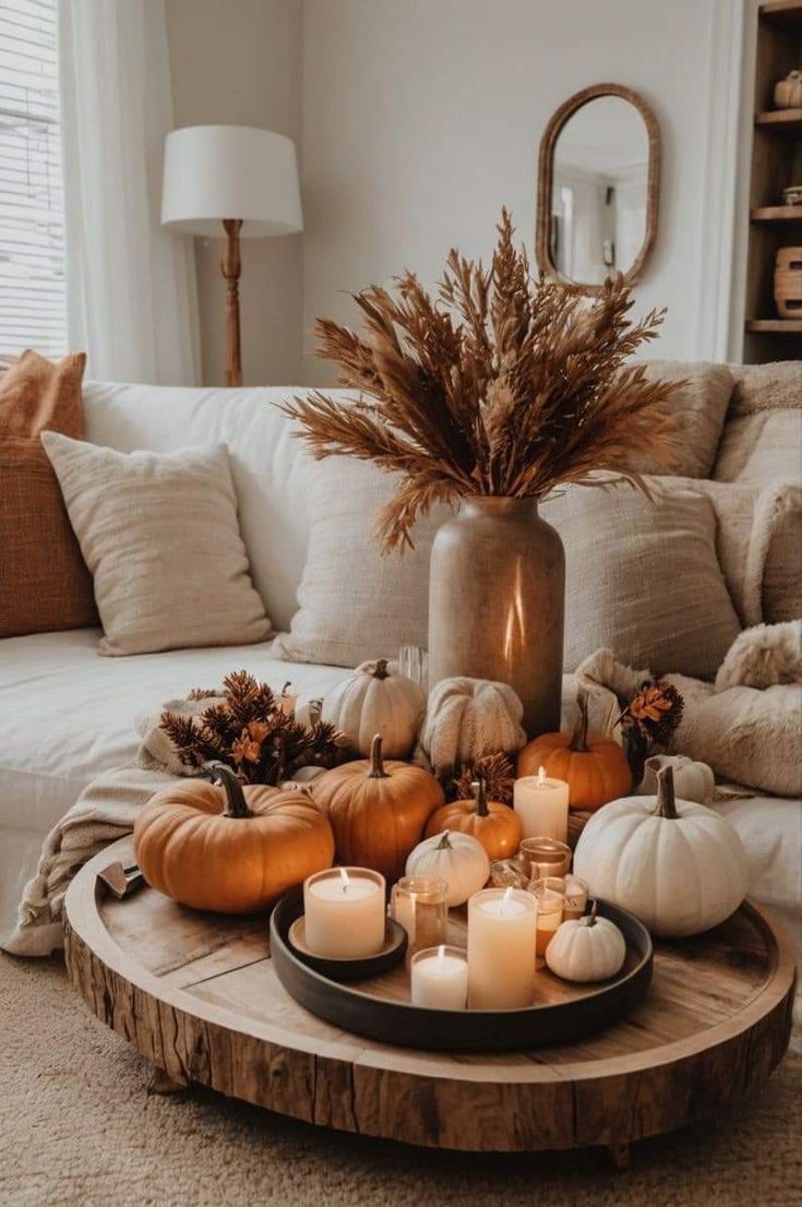 a coffee table with candles and pumpkins on it in front of a white couch