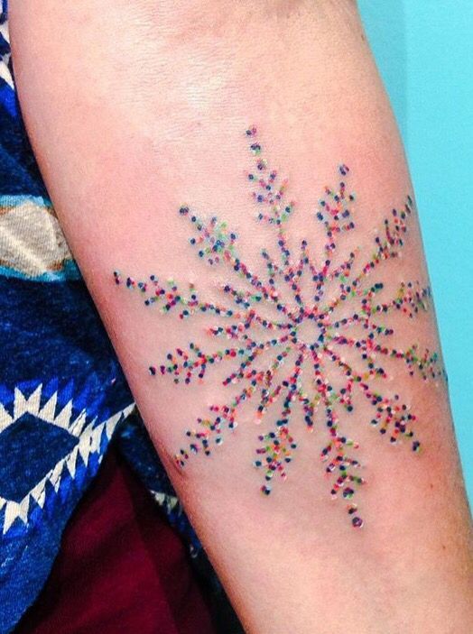 a person with a tattoo on their arm that has an image of a snowflake