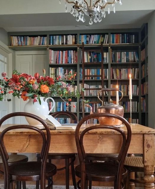 a dining room table with chairs and a vase filled with flowers on top of it