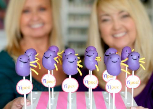 two women are holding up some cake pops