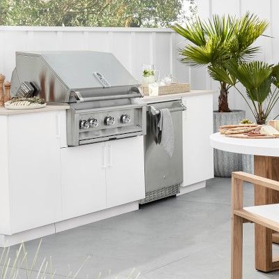 an outdoor kitchen with white cabinets and stainless steel appliances, including a bbq grill