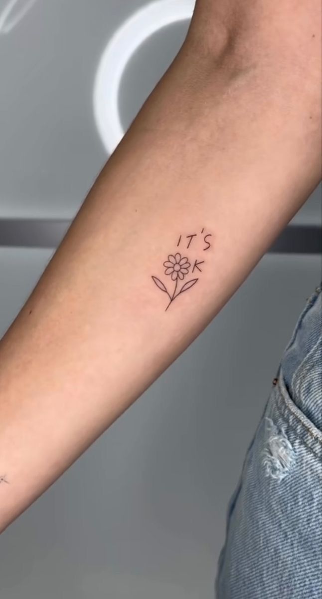 a woman's arm with a small flower tattoo on the left side of her arm