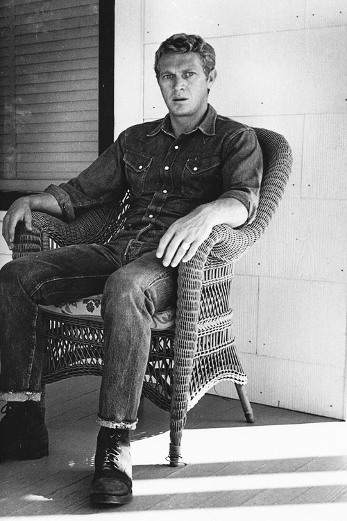 a man sitting on top of a wicker chair next to a wall and door