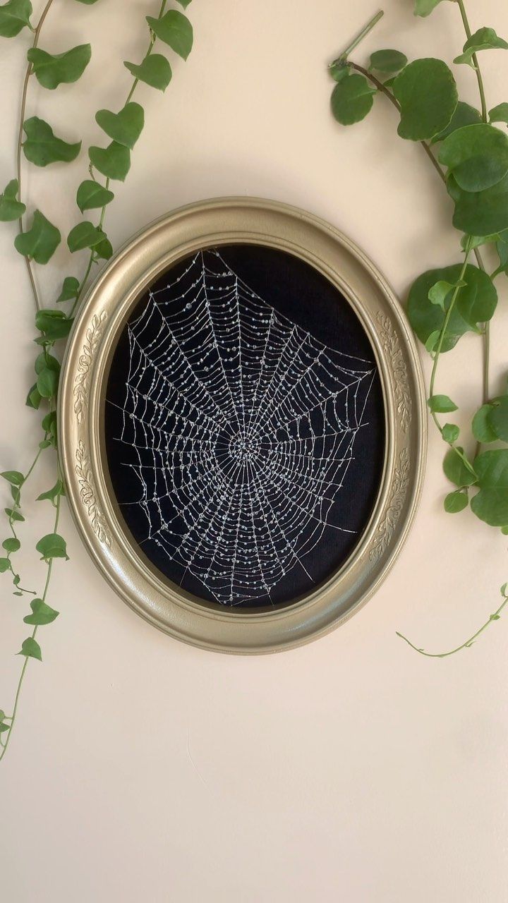 a spider web in a metal frame surrounded by green leaves