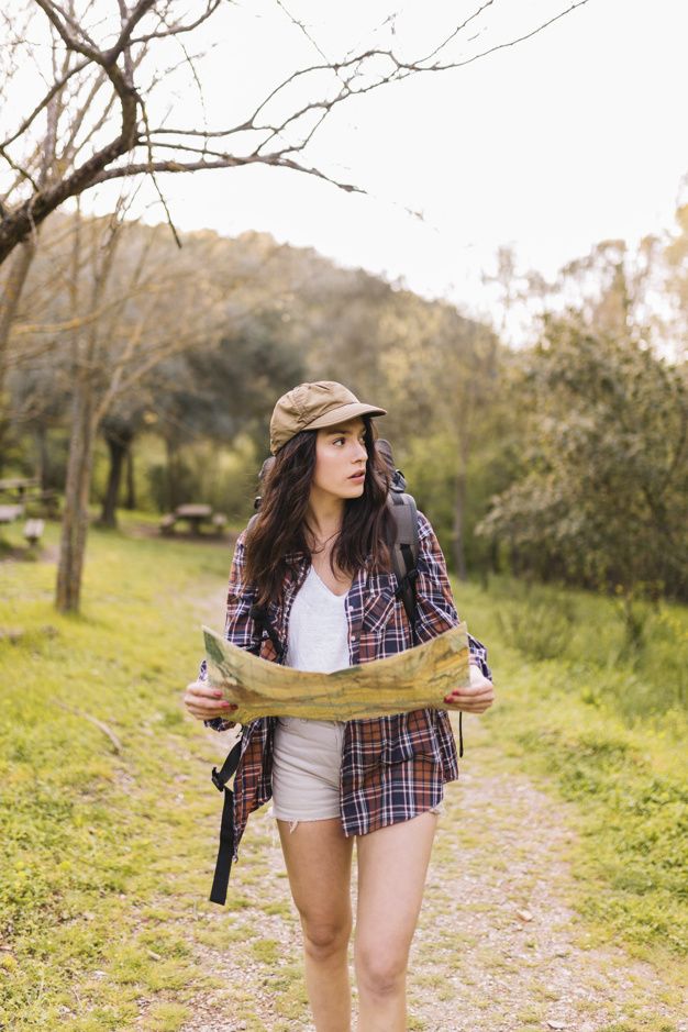 a woman walking down a dirt road with a hat on