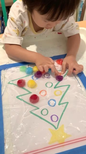 a young child is making a christmas tree art project