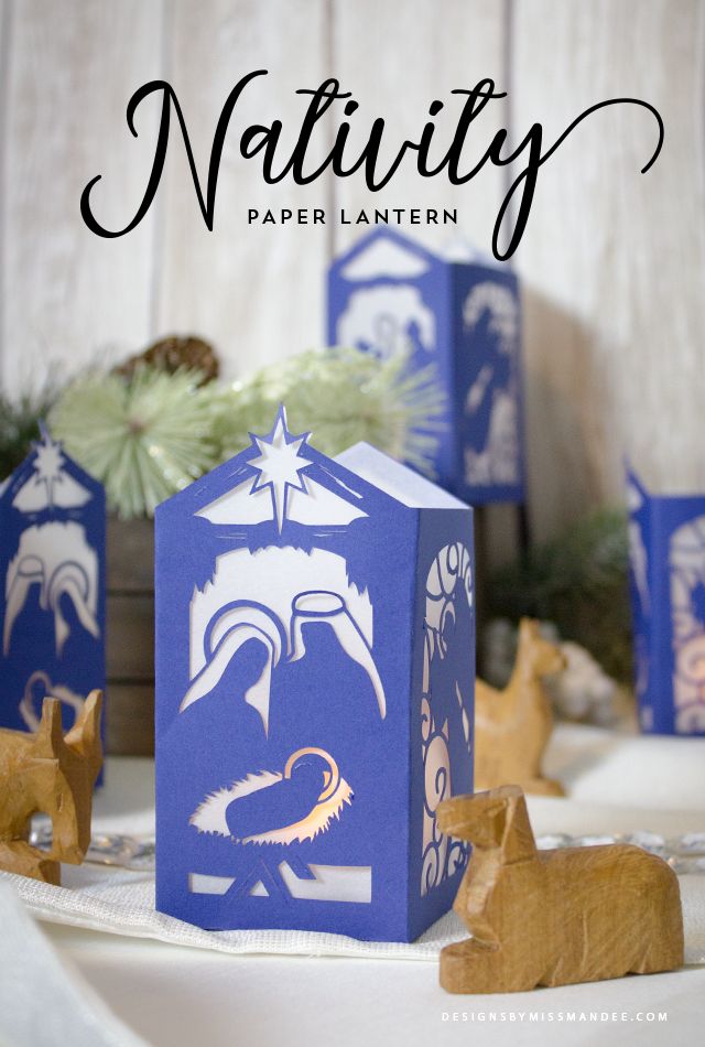 nativity paper lantern in blue and white with wooden animals on the table next to it